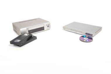 Beyaz arkaplanda izole edilmiş DVD oynatıcı ve DVD 'lerin yanında video oynatıcı ve kasetler.