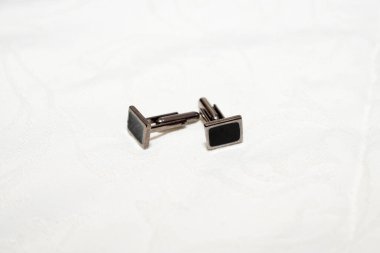 Beyaz arka planda bir çift metal kol düğmesi. Erkek modasına ait nesnelerin görünümünü kapat.