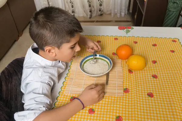 Çocuk sol eliyle sütlaç yiyor..