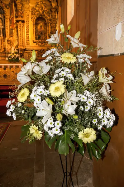 Floral decoration with yellow and white flowers adorning the interior of a church. Gerberas, lilies, calendulas and daisies.