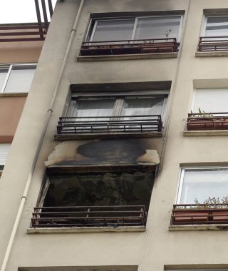 Ev, bir apartmanın penceresinden çıkan yangınla yanmış..