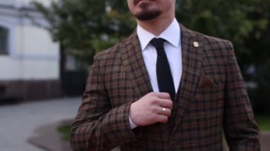 Kareli takım elbiseli bir adam sokakta yürüyor.