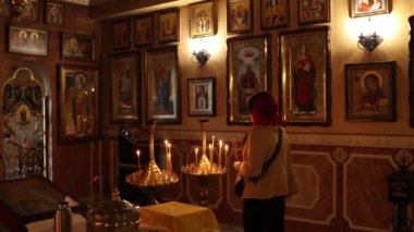 Bir kız kilisede mum yakıyor.