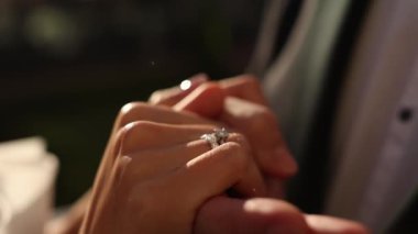 Bir erkek, bir kadının elini güneşin arka planında tutar.