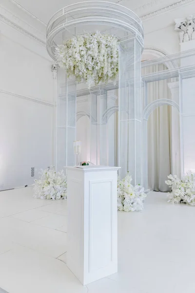 an indoor wedding ceremony arch with table and flowers
