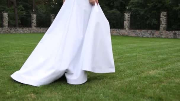 花嫁は結婚式の緑の芝生の上を裸足で歩き — ストック動画