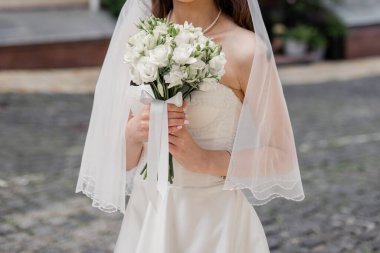 bride in a white dress with a wedding bouquet on a city street
