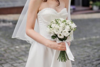 bride in a white dress with a wedding bouquet on a city street