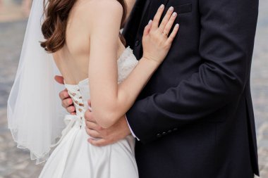 groom and the bride in a wedding dress stand together on the street