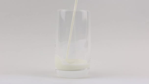 Λευκό Φρέσκο Γάλα Χύνεται Ένα Διαφανές Ποτήρι Λευκό Φόντο — Αρχείο Βίντεο