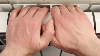 Erkek elleri metalin üzerinde, sıcak, sıcak ısıtıcı radyatör soğuktan ellerini ısıtıyor.