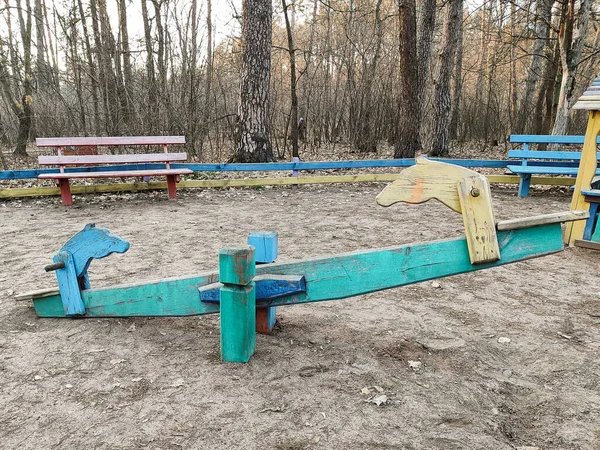 an old wooden swing on the playground in the forest in the park