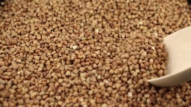 Karabuğday, ahşap bir kaşıkta yetişir ve yemek pişirmek için arka plandaki yemek videolarını döker.