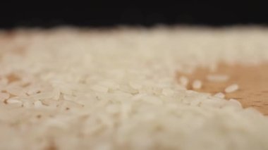 Masaya beyaz pirinç tanecikleri dökülüyor. Japon mutfağı için yavaş yavaş arka plan ekran koruyucusu.