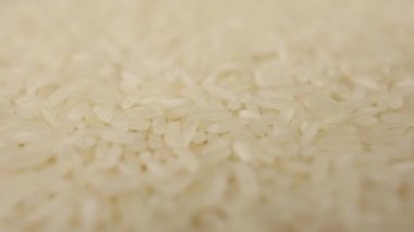Masaya beyaz pirinç tanecikleri dökülüyor. Japon mutfağı için yavaş yavaş arka plan ekran koruyucusu.