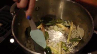 Aşçı yemek pişirirken tavadaki sebzeleri spatulayla karıştırır.