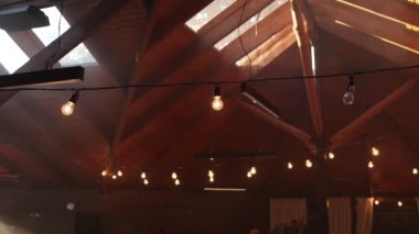 Restoran terasının ahşap tavanında ampuller.