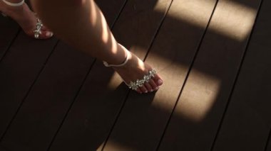 Gelin kadın ayakkabılarını giymiş, tahta zeminde yürüyor.