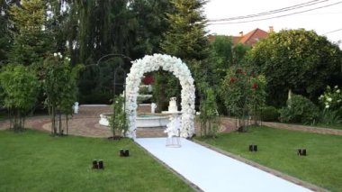 Güzel düğün pastası, kemerin yanında, akşamları çiçekli.