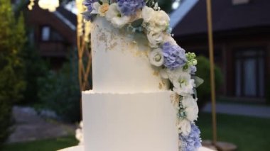 Düğün kemerinin yanında büyük beyaz bir düğün pastası.