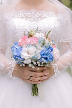 Beyaz elbiseli gelin düğünde bir buket tutuyor.