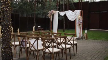 Sandalyeli bir parkta düğün töreni için güzel bir kemer.