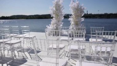 Nehir kıyısında sandalyeleri olan bir düğün kemeri.