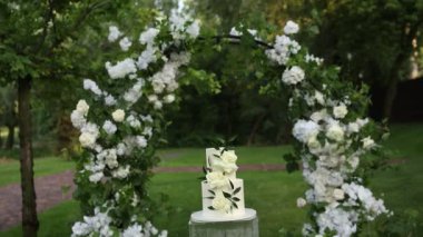 Tören için kemerin yanında güzel beyaz düğün pastası.