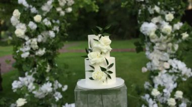 Tören için kemerin yanında güzel beyaz düğün pastası.