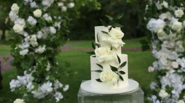 Tören için kemerin yanında güzel beyaz düğün pastası.