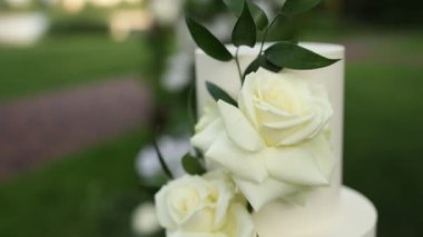 Tören için kemerin yanında güzel beyaz düğün pastası.