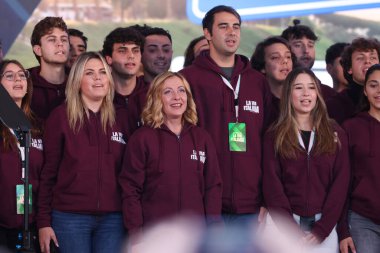 Rome, Italy 15.12.2024:  Prime minister of italy Giorgia Meloni  sing the national anthem with the young volunteers dressed in dark red fleeces at end of  the political event organized by the governing party Fratelli D'Italia called Atreju 2024 at th clipart