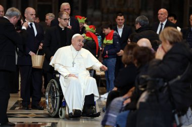 Roma, İtalya 06.01.2025: Papa Francis Bergoglio tekerlekli sandalyeyle uzaklaşıyor ve çocukları selamlıyor, Kutsal Ayin 'in günah çıkarma sunağı Aziz Peters Bazilikası' nda yapılan ayinden sonra sadık kalamıyor.
