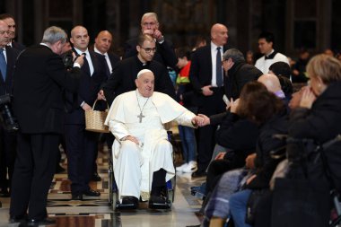 Roma, İtalya 06.01.2025: Papa Francis Bergoglio tekerlekli sandalyeyle uzaklaşıyor ve çocukları selamlıyor, Kutsal Ayin 'in günah çıkarma sunağı Aziz Peters Bazilikası' nda yapılan ayinden sonra sadık kalamıyor.