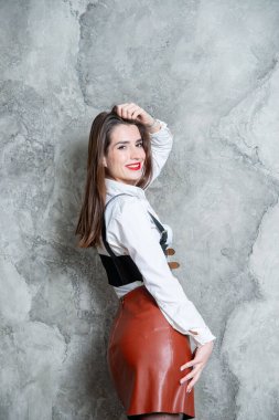 Stüdyoda gri duvara karşı poz veren güzel seksi kadın.