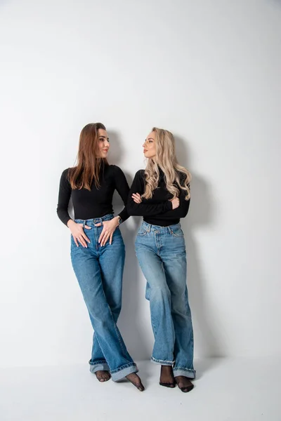 stock image two beautiful girls brunette and blonde posing in studio against gray