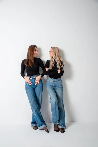 stock image two beautiful girls brunette and blonde posing in studio against gray