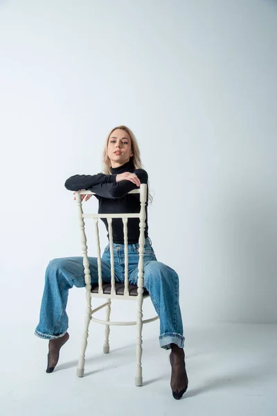 beautiful blonde woman posing on chair in studio