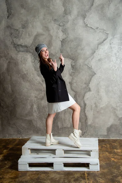 美しい若い女性は白いドレス 黒のジャケットとグレーの帽子を身に着けてスタジオでポーズ — ストック写真
