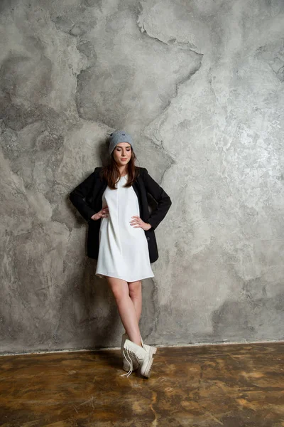美しい若い女性は白いドレス 黒のジャケットとグレーの帽子を身に着けてスタジオでポーズ — ストック写真