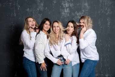young attractive women in white shirts and jeans posing in the studio