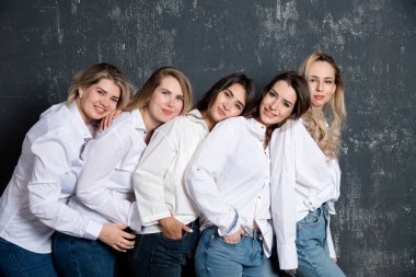young attractive women in white shirts and jeans posing in the studio