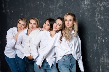 young attractive women in white shirts and jeans posing in the studio