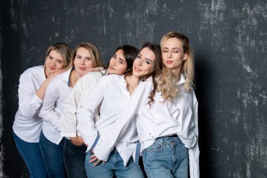 young attractive women in white shirts and jeans posing in the studio