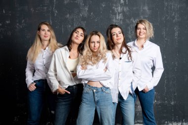 young attractive women in white shirts and jeans posing in the studio