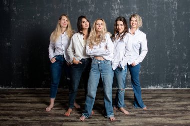 young attractive women in white shirts and jeans posing in the studio
