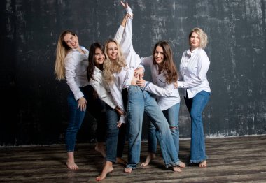 young attractive women in white shirts and jeans posing in the studio