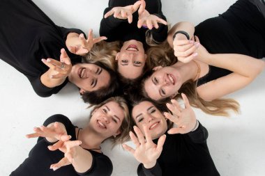 Group of young women lying in a circle, laughing, hugging, having fun, hands