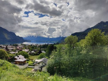 A magical landscape in Austria featuring a serene lake surrounded by majestic mountains, under a sky filled with fluffy clouds that reflect the beauty of nature. clipart