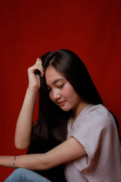 Asian woman taking photo on a red background. Happy Asian woman. Beautiful asian woman with long and straight hair.